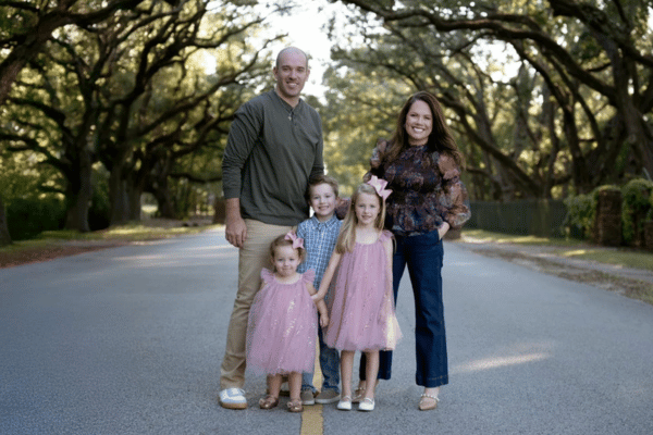 Teacher Molly Biffle poses on their tree-lined street with her husband and three young children who benefited from a docked pay reimbursement grant